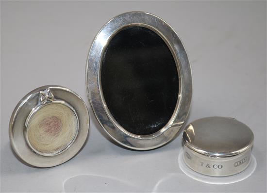 A small Tiffany silver pill box and two small photograph frames.